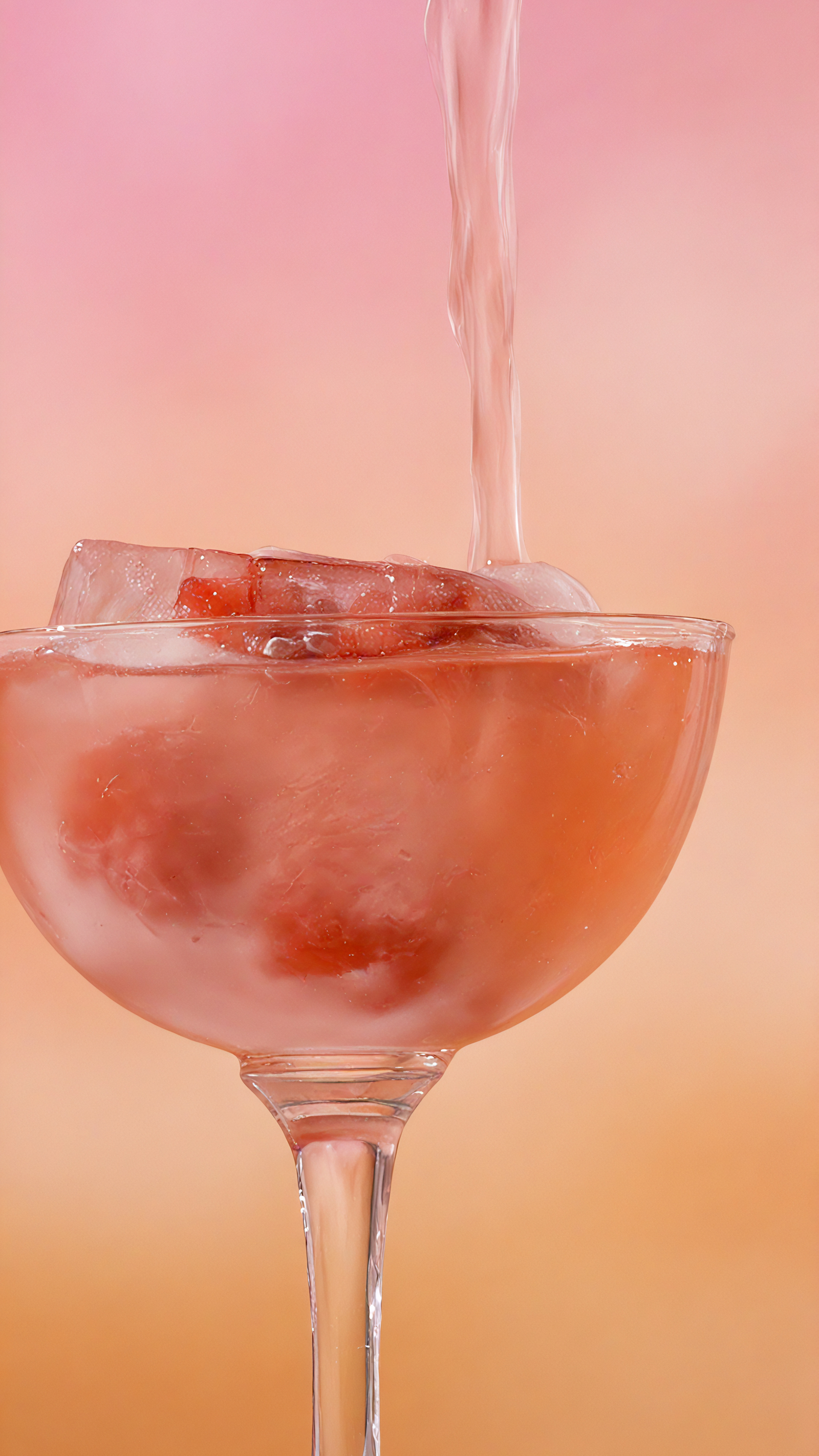 Glass of pink cocktail with ice and strawberries being poured against a gradient background